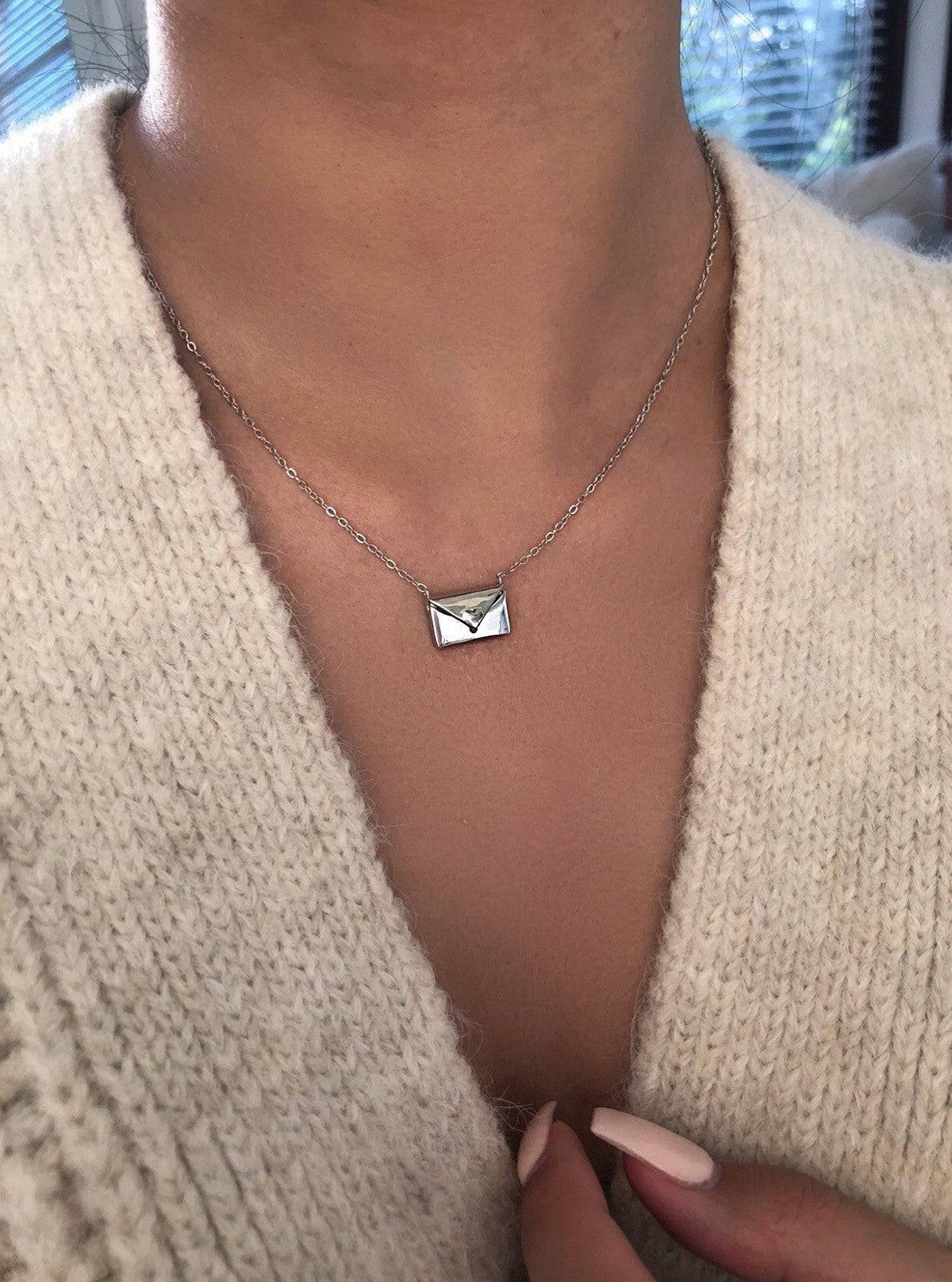 Beckett Envelope Pendant Necklace featuring a delicate metal envelope charm on a sleek chain, close-up view of the jewelry.